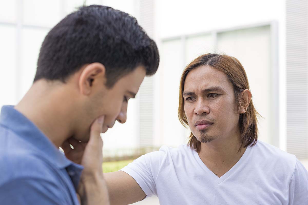two men looking concerned while having a serious discussion about outpatient treatment for addiction