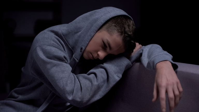 a young person wearing a hoodie appears distraught and struggling with opiate abuse